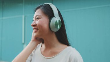 Kulaklık takmış, günlük giysiler giymiş, müzik dinleyip şarkı söyleyen güzel bir esmer kız.