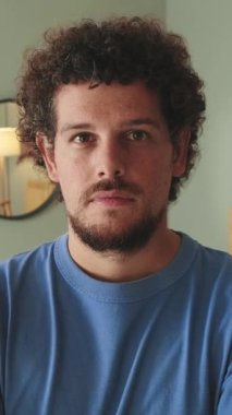 Genç adam gülümseyerek kameraya bakıyor.