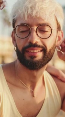 Yakından, gözlüklü, sakallı ve beyaz saçlı adam biriyle konuşuyor.