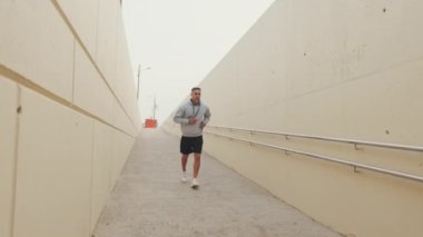 Spor giyimli orta yaşlı bir adam dışarıda koşuyor.