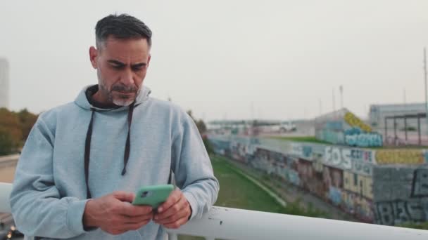Homem Meia Idade Sportswear Usa Telefone Celular Enquanto Está Ponte — Vídeo de Stock