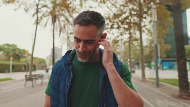 Pria Paruh Baya Mendengarkan Musik Dengan Earphone Nirkabel Sambil Berjalan — Stok Video