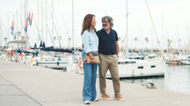 Yaşlı bir çift gezinti güvertesinde yürüyor ve yat arka planında sohbet ederken eğleniyor.