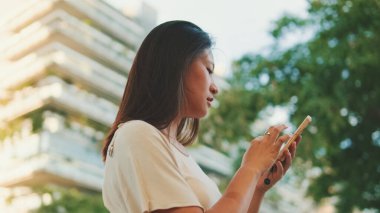 Gayri resmi giyinmiş güzel esmer kız, cep telefonunda kart başvurusu.