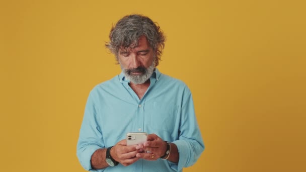 Elderly Gray Haired Smiling Man Uses Mobile Phone Isolated Orange — Stock Video