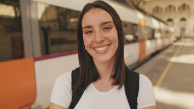 Tren istasyonunda kameraya gülümseyen bir kadının yakın çekimi.