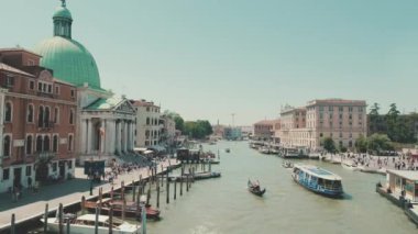Venedik 'teki kanal, güneşli bir günde turistlerle dolu tekneler ve gondollar kanal boyunca yüzer.