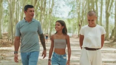 Mutlu bir aile parkta yürüyor ve konuşuyor.