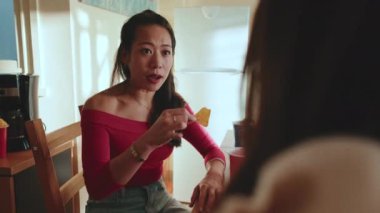 İki kız arkadaş masada oturmuş abur cubur yiyor.