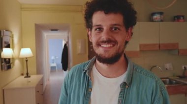 Kameraya bakan gülümseyen genç adamın yakın çekimi.