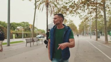 Orta yaşlı bir adam kablosuz kulaklıklarla müzik dinliyor.