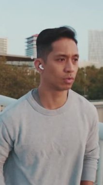 Sabah koşusunda kablosuz kulaklıklı genç adam.