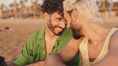 Birbirine aşık eşcinsel çiftler şafak vakti kumsalda oturarak vakit geçirirler.