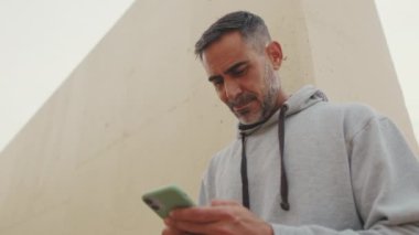 Yakından, spor kıyafetleri içinde orta yaşlı bir adam eğitimden sonra cep telefonuna SMS mesajı yazıyor.