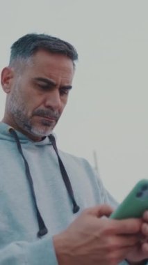 Spor giyim sektöründe orta yaşlı bir adam sokakta yürürken cep telefonu kullanıyor.