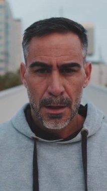 Yakından, orta yaşlı bir adam spor giyim bölümünde kameraya bakıyor.