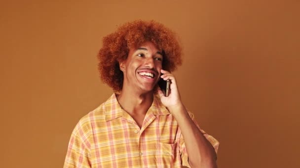 Сміється Хлопець Емоційно Говорить Мобільному Телефоні Ізольований Коричневому Фоні Студії — стокове відео