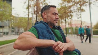 Yaklaş, orta yaşlı adam parkta bankta dinleniyor.