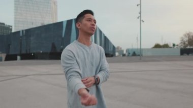 Genç sporcu ısınıyor, spor saatini kontrol ediyor ve koşuya başlıyor.