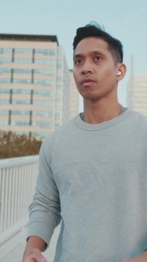 Telsiz kulaklıklı genç adam elinde cep telefonuyla köprü boyunca yürüyor.