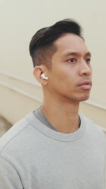 Telsiz kulaklıklı genç adam yürür ve saatine bakar.