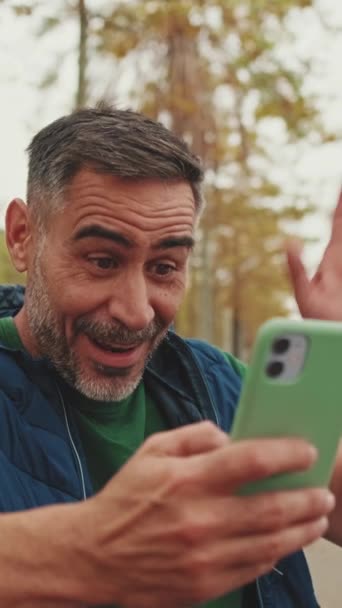 Medelålders Man Sitter Bänken Och Pratar Videosamtal Från Mobiltelefon — Stockvideo