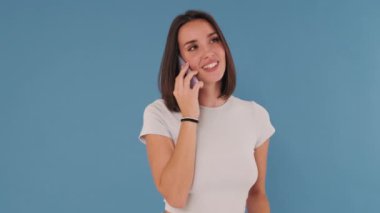 Genç bayan, cep telefonuyla konuşurken şaşırdı, mutlu haber, Mavi Arka plan 'da izole edilmiş.