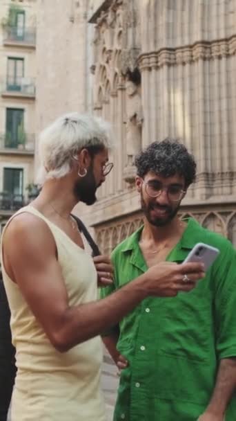 Homosexual Couple Uses Mobile Phone While Discussing Something While Standing — Stock Video