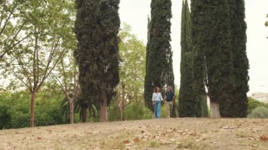 Yaşlı bir çift el ele tutuşarak parkta yürüyor.