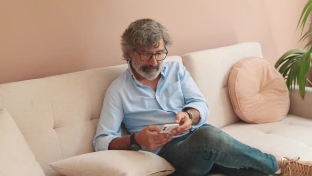 Seorang Pria Tua Duduk Sofa Ruang Tamu Nyaman Dengan Telepon — Stok Video
