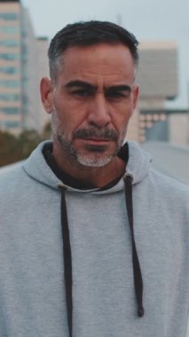 Yakın plan, orta yaşlı spor kıyafetli bir adam kameraya bakıyor, kamera ileri gidiyor.