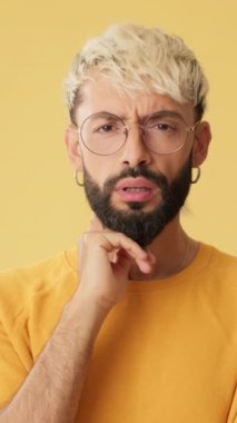 Adam dikkatlice dinler ve kategorik olarak katılmaz. Stüdyoda sarı arka planda izole olur.