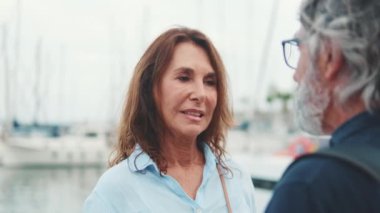 Güzel, yaşlı bir kadının limanda dikilip erkek arkadaşıyla konuşmasının yakın çekimi.