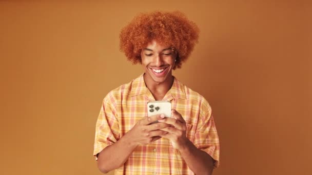 Gülümseyen Adam Cep Telefonuna Mesaj Yazıyor Stüdyoda Kahverengi Arka Planda — Stok video