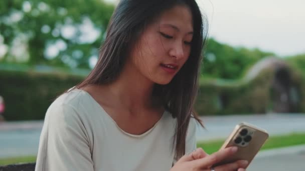 Ung Kvinna Som Använder Mobiltelefon När Hon Sitter Bänken Utanför — Stockvideo