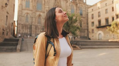 Sırt çantasıyla gezgin kız, Avrupa 'nın tarihi bölgesinin meydanında durduğu zaman bakıyor.