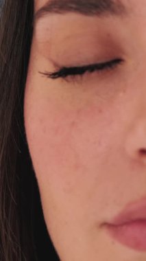 Genç bir kadının gözlerini açıp kameraya bakarken yüzünün yarısının detaylı görüntüsü.