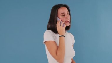 İyi haberlerim var, genç bayan. Mavi Arkaplanda İzole Edilmiş 'in cep telefonuyla konuşurken şaşırdım.