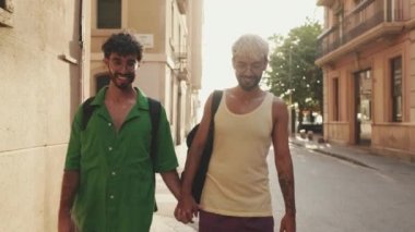 Mutlu eşcinsel çift sokakta el ele yürüyor.