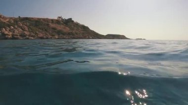 Kıyı kayaları olan su yüzeyi, alçak açılı çekim, arka plan ışığı, deniz manzarası