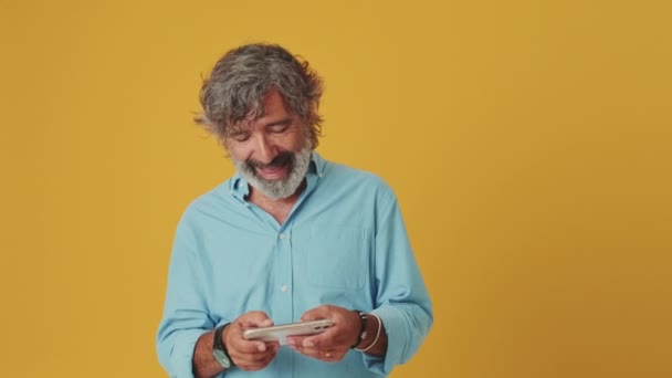 Anciano Sonriente Hombre Pelo Gris Jugando Videojuegos Teléfono Móvil Aislado — Vídeos de Stock