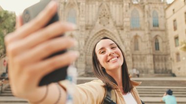 Yakın plan, gezgin kız eski Avrupa kentinin tarihi bölümündeki eski binada cep telefonuyla selfie çekiyor.