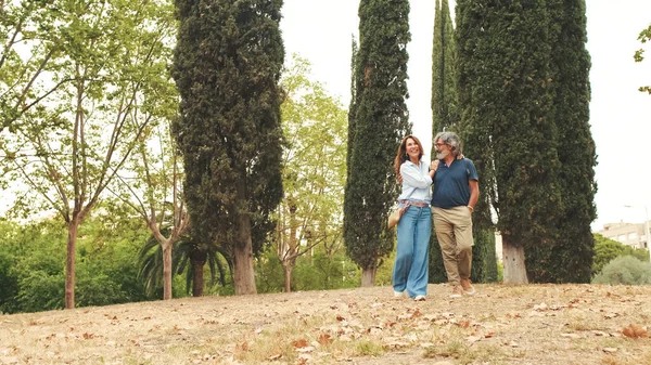 Mutlu yaşlı evli çift parkta el ele yürüyor.
