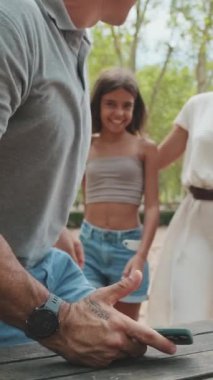 Parktaki bankta oturan bir adam ailesini selamlamaktan mutluluk duyar.