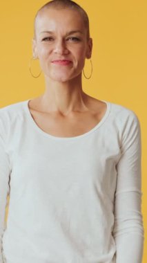 Kalbi temsil eden genç bir kadın. Stüdyoda sarı arka planda izole edilmiş kameraya bakıyor.