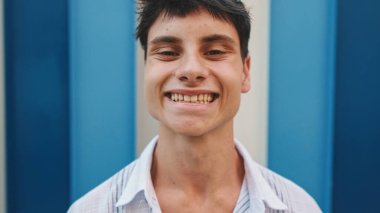 Yaklaş, günlük kıyafetler giymiş adam kafasını kaldırıyor, gözlerini açıyor ve çizgili arka plandaki kameraya bakıyor.