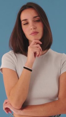 Genç bir kadın kameraya bakar ve stüdyonun mavi arka planında izole edilmiş olarak kabul eder.