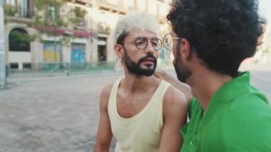 İki erkek turist sokakta otururken sohbet ediyorlar.