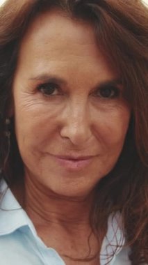 Kameraya bakarken gülümseyen yaşlı güzel kadının yakın çekimi.