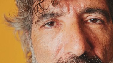 Yakın plan, yaşlı, gri saçlı bir adamın gözü gözlerini açıyor ve kameraya bakıyor.